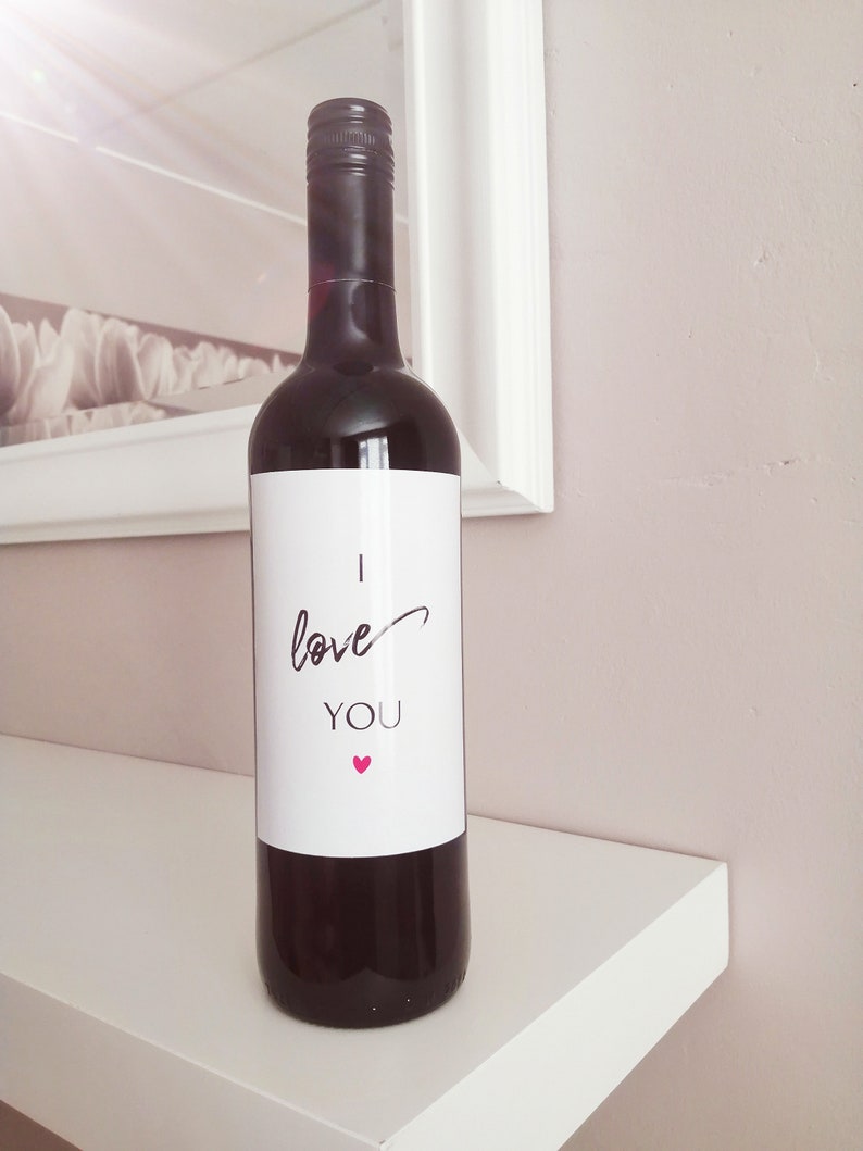 Pu&ograve; includere: Una bottiglia di vino rosso con un'etichetta bianca che dice "Ti amo" con un piccolo cuore rosa.