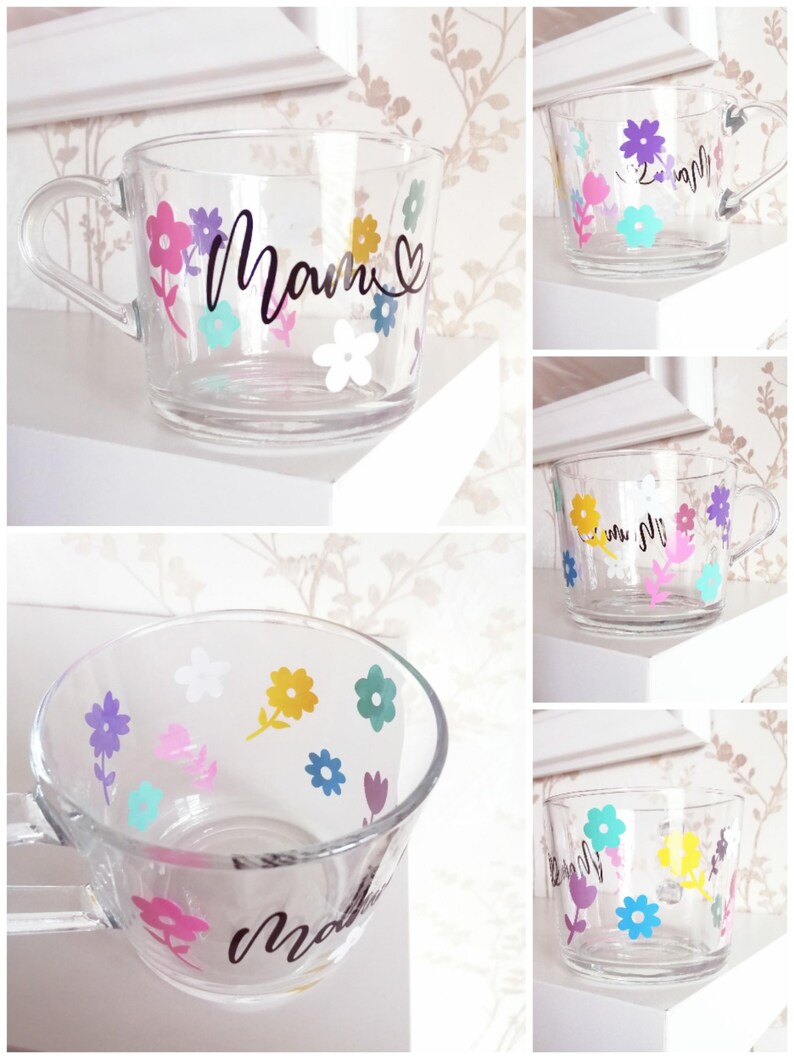 May include: A clear glass mug with a black floral design and the word "Mamm" written on it. The mug is decorated with colorful flowers.