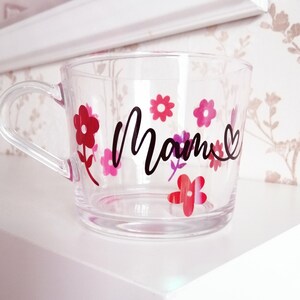 May include: Clear glass mug with a black "Mom" design and pink and red flower decals.