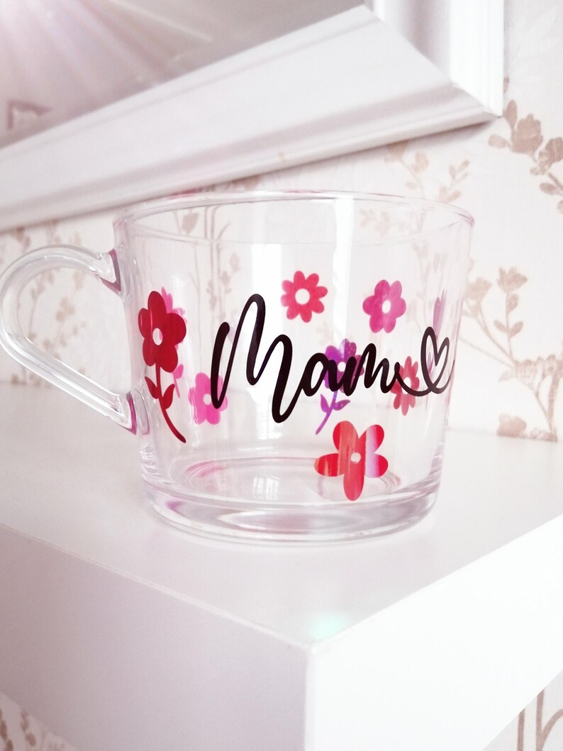 May include: Clear glass mug with a black "Mom" design and pink and red flower decals.