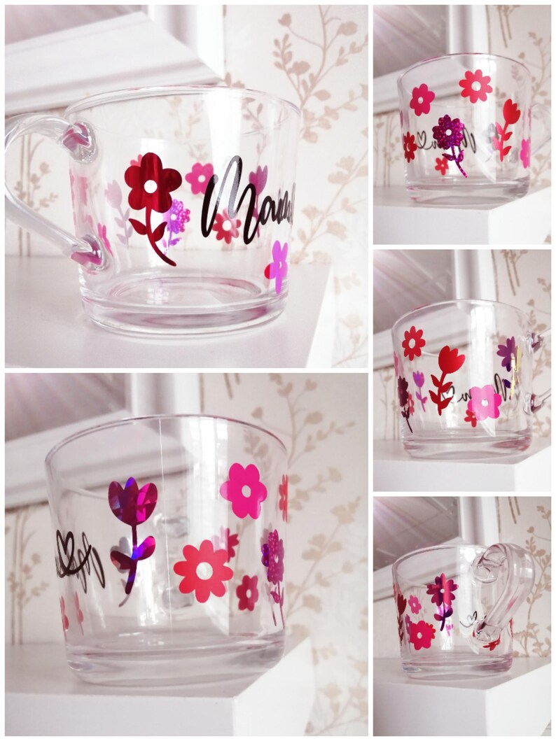 May include: A clear glass mug with a handle decorated with pink and red flowers and the word "Mama" in black lettering.