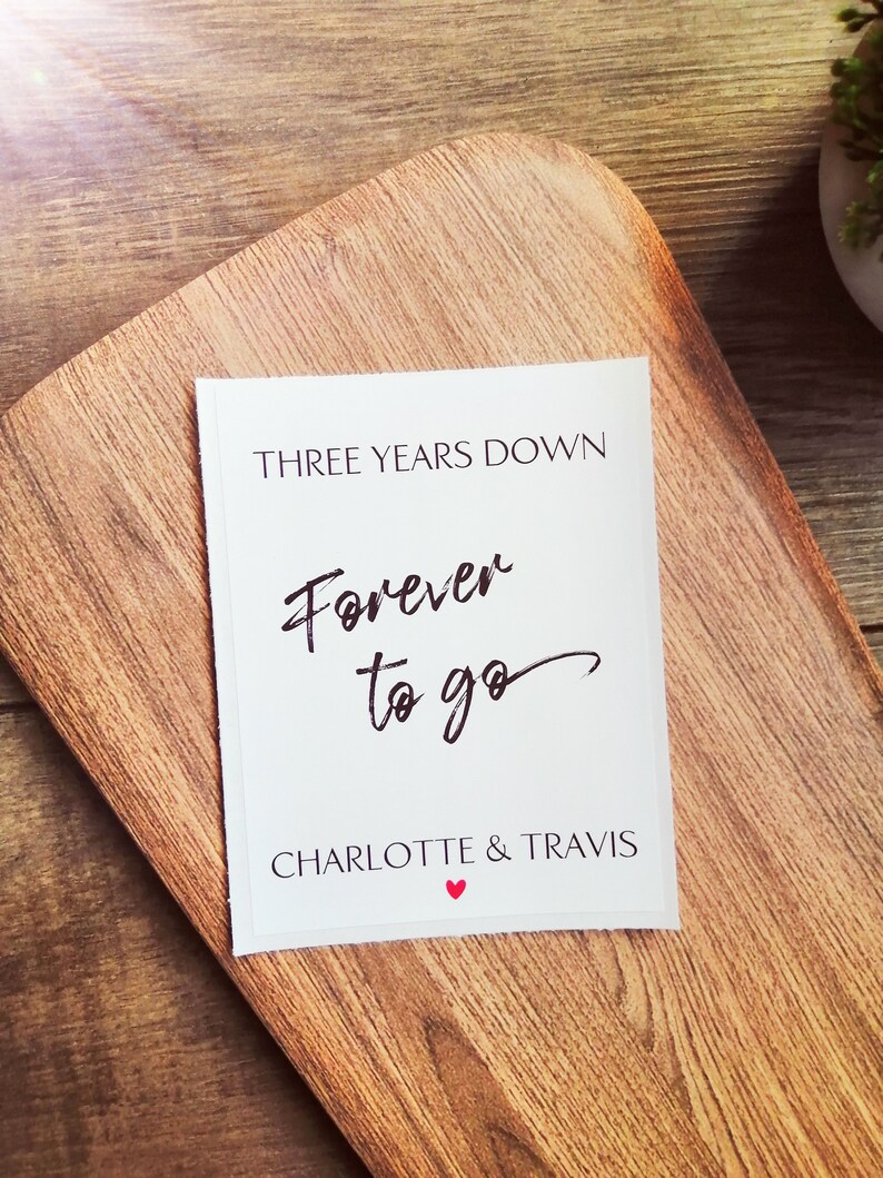 Pu&ograve; includere: Carta bianca con testo nero che dice "Three Years Down Forever to go Charlotte & Travis" con un simbolo di cuore rosso.