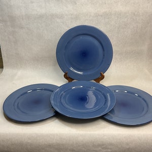 May include: Four blue ceramic plates. Three plates are arranged in a row, with the fourth plate propped up behind them. The plates have a slightly textured surface and a deep blue color.