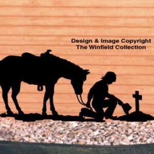 May include: A black silhouette cutout featuring a saddled horse standing beside a person kneeling before a small cross. The text Design & Image Copyright The Winfield Collection is printed in black above the horse and person figures.