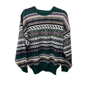 May include: A green, purple, and beige patterned sweater. The sweater features a crew neck and long sleeves. The design includes geometric shapes and stripes in shades of green, purple, beige, and white. The sweater is made of a soft, knitted material.