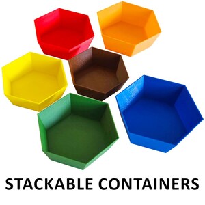 Può includere: Sei contenitori impilabili esagonali dai colori vivaci: rosso, arancione, giallo, marrone, verde e blu. Il testo "STACKABLE CONTAINERS" è stampato in nero nella parte inferiore dell'immagine.