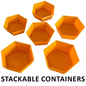 Può includere: Sei contenitori impilabili esagonali arancioni brillanti sono mostrati su uno sfondo bianco. I contenitori sono vuoti e hanno un design semplice e moderno. Il testo "STACKABLE CONTAINERS" è stampato in nero nella parte inferiore dell'immagine.
