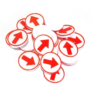 Puede incluir: Un montón de señales de tráfico circulares rojas y blancas con flechas que apuntan en diferentes direcciones. Las señales son de plástico y tienen un fondo blanco con un borde rojo y una flecha.