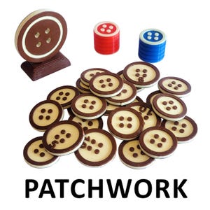 May include: A set of brown and white button-shaped game pieces for the board game Patchwork. The pieces are arranged in a pile with a brown button-shaped game piece on top. There are also two stacks of colored dice, one red and one blue.