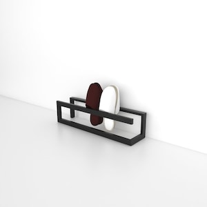 May include: A black metal shoe rack with two pairs of slippers, one white and one burgundy, hanging on it.