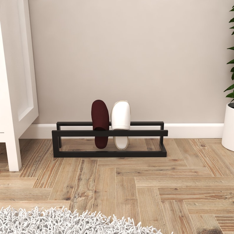 May include: A black metal shoe rack with two pairs of slippers on it. One pair is white and the other is burgundy.