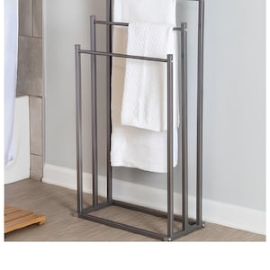 May include: A three-tiered towel rack made of metal with a dark grey finish. The rack has three horizontal bars for hanging towels and a rectangular base.