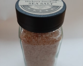 May include: A glass jar filled with pink Himalayan sea salt, labeled "Hickory Smoked Sea Salt". The label has a vintage design with stars and the words "Ingredients: Pink Himalayan Sea Salt".