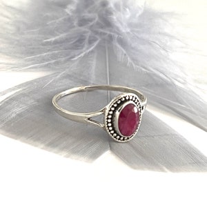 Könnte beinhalten: Ein silberner Ring mit einem rosafarbenen ovalen Edelstein, der in einer Perlenfassung sitzt. Der Ring hat einen zarten geteilten Schaft.