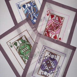 Könnte beinhalten: Vier Stickvorlagen mit Spielkartenmotiven: ein blauer Pik-König, eine rosa Herz-Dame, ein grüner Kreuz-Bube und ein violetter Joker. Jede rechteckige Leinwand hat einen weißen Gitterhintergrund und einen festen grauen Stoffrand.