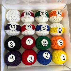 May include: A set of 15 crocheted billiard balls in a clear plastic box. The balls are numbered 1 through 15 and are in various colors, including white, red, blue, green, yellow, and orange.