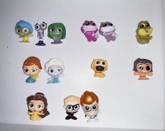 Puede incluir: Una colección de 12 pequeñas figuras de plástico de personajes populares de Disney. Los personajes incluyen: Alegría, Tristeza, Ira, Asco, el Gato de Cheshire, Elsa, Anna, Dug, Moana, Bella, Flash y Violeta.