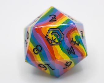 Könnte beinhalten: Ein zwanzigseitiger Würfel mit Regenbogenstreifen. Der Würfel hat schwarze Zahlen und Symbole auf jeder Seite. Auf einer Seite befindet sich ein schwarzes Symbol. Ein Spielzubehör.