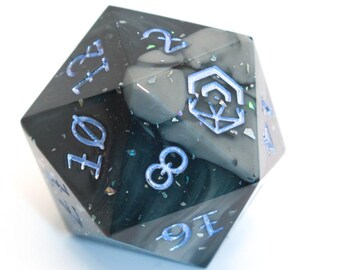 Könnte beinhalten: Ein großer, vielseitiger, marmorierter Würfel mit einem dunkelgrauen und schwarzen Farbschema. Der Würfel hat hellblaue Zahlen und ein geometrisches Symbol. Iridescent glitzernde Akzente sind verstreut. Ideal für Tabletop-Spiele.