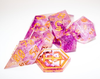 Könnte beinhalten: Ein Satz rosa und weißer Würfel mit goldenem Glitzer und goldenen Zahlen. Die Würfel haben verschiedene Formen, darunter ein W4, W6, W8, W10, W12 und W20.