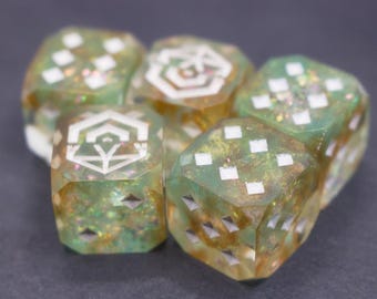 Könnte beinhalten: Eine Sammlung von sechsseitigen Würfeln mit einem durchscheinenden grünen und goldenen Glitzereffekt. Jeder Würfel hat weiße geometrische Symbole und weiße quadratische Augen. Die Würfel sind für Tischspiele konzipiert.