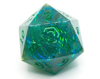 Könnte beinhalten: Ein großer, irisierender grün-blauer D20-Würfel mit weißen Zahlen. Der Würfel hat ein schimmerndes, glitzerndes Inneres und ein geometrisches Design auf einer Seite. Ideal für Tabletop-Spiele.