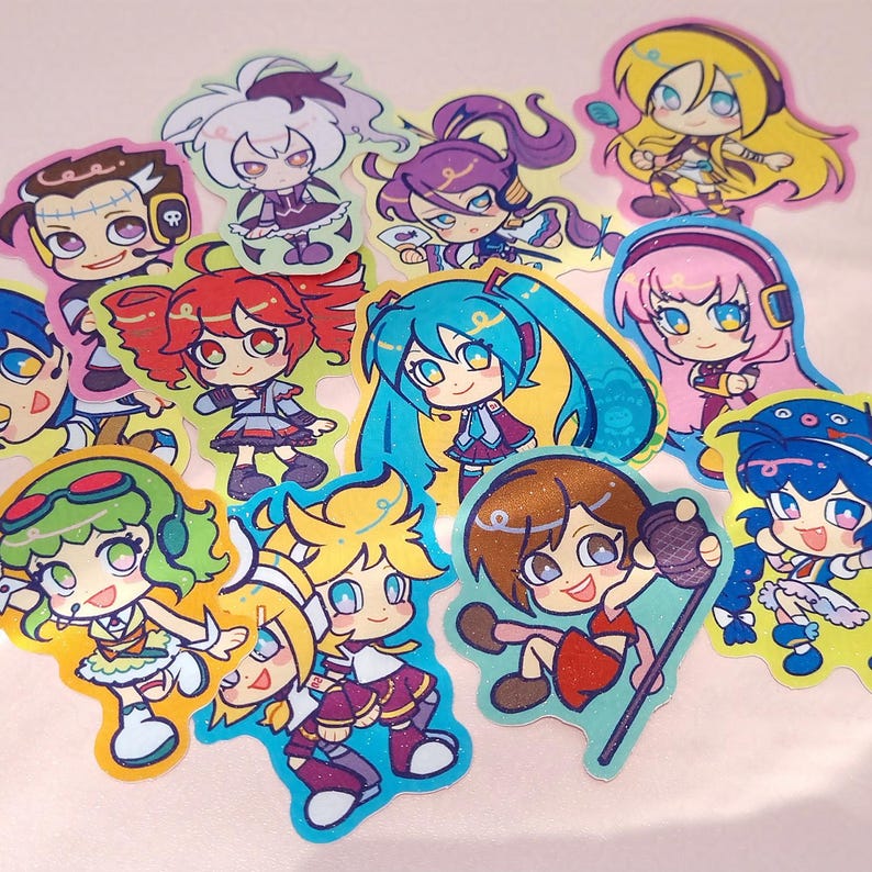 Photo of glittery stickers by marinewaltz. They are bright and colourful, and feature these synths: Hatsune Miku, Kagamine Rin and Len, Megurine Luka, SynthV Kasane Teto, Kamui Gakupo, GUMI, KAITO, MEIKO, VFlower, Big Al, Lily and Otomachi Una.