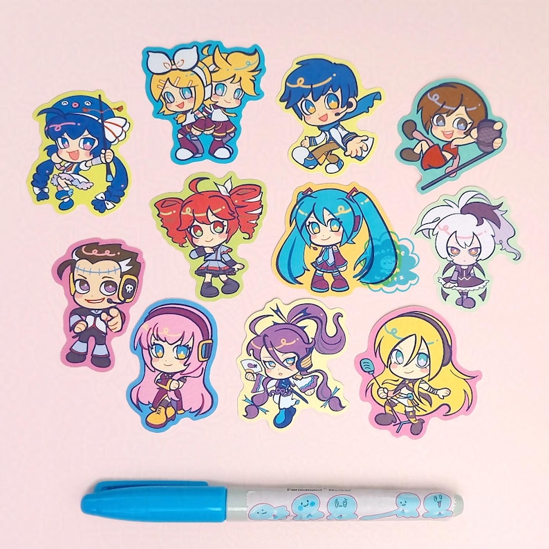 Photo of glittery stickers by marinewaltz. They are bright and colourful, and feature these synths: Hatsune Miku, Kagamine Rin and Len, Megurine Luka, SynthV Kasane Teto, Kamui Gakupo, GUMI, KAITO, MEIKO, VFlower, Big Al, Lily and Otomachi Una.