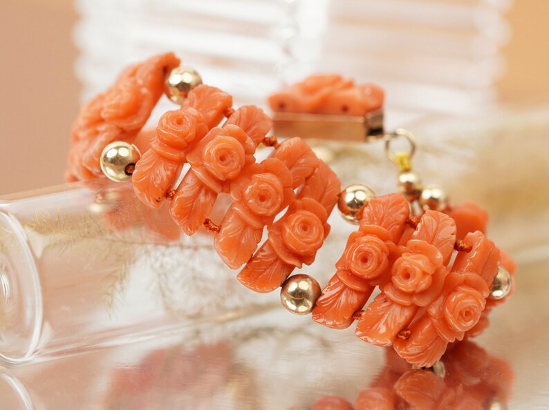 May include: A coral bracelet with carved rose and leaf details, strung with gold beads.
