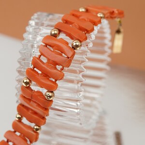 May include: A coral bracelet with gold beads. The bracelet is made of orange coral and has a gold clasp.