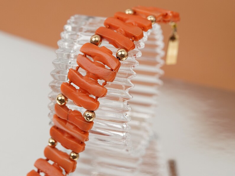 May include: A coral bracelet with gold beads. The bracelet is made of orange coral and has a gold clasp.