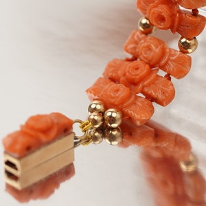 May include: A coral bracelet with gold beads and a rose design. The bracelet has a clasp made of gold.