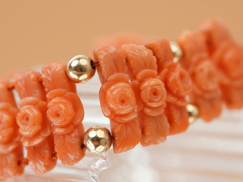 May include: A coral bracelet with carved rose motifs and gold beads.