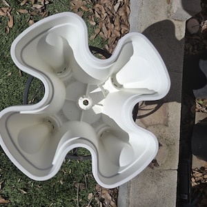 May include: White plastic planter with five separate compartments for planting. The planter is shaped like a flower with five petals.