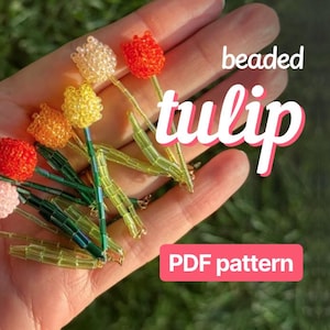 以下が含まれることがあります： 赤、ピンク、黄色、オレンジなど、さまざまな色のビーズのチューリップの花のコレクション。茎は緑色で、花は手で持たれています。画像には「beaded tulip」と「PDF pattern」の文字が含まれています。
