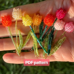 Peut inclure: Un ensemble de fleurs de tulipes perlées de différentes couleurs, dont orange, jaune, rose et blanc. Les tiges sont vertes et dorées. Le texte "PDF pattern" est affiché sur un fond rouge.