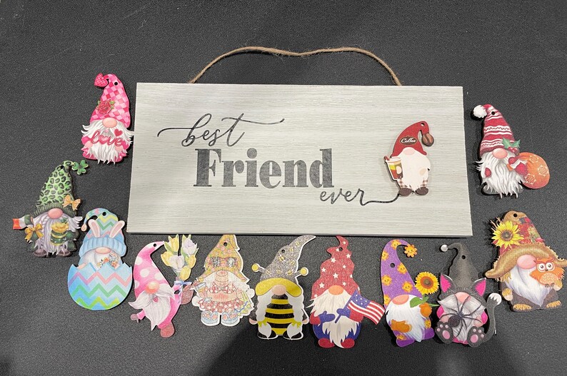 May include: A wooden sign with the words "Best Friend ever" and several gnome-shaped decorations. The gnomes are colorful and feature various designs, including flowers, coffee cups, and patriotic themes.