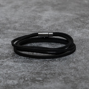 May include: A black leather wrap bracelet with a silver magnetic clasp.