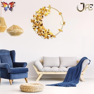 May include: A gold metal wall decor featuring a circular frame with a cluster of butterflies arranged in a crescent shape. The butterflies are made of metal and have a shiny finish. The wall decor is hanging on a white wall in a living room setting.