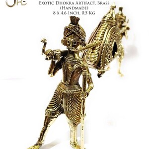 May include: A gold-colored brass sculpture of a person carrying a palanquin, a type of covered litter, on their shoulders. The sculpture is handmade and measures 8 inches by 4.6 inches. The sculpture is called "The Paalki" and is an example of the Dhokra art form.