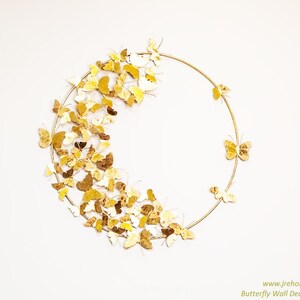 May include: Gold butterfly wall decor with a circular metal frame. The butterflies are arranged in a semi-circle around the frame. The decor measures 24x24 inches and weighs 1.7 kg.