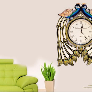 May include: A wooden wall clock featuring two peacocks with blue, green, and gold painted feathers. The clock face is white with black Roman numeral markings and a gold trim. The clock measures 24x18 inches and weighs 2.5 pounds.