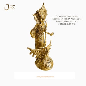 May include: A gold-colored brass sculpture of the Hindu goddess Saraswati, the goddess of knowledge, music, and art. She is depicted standing on a bird, holding a book and a musical instrument. The sculpture is 7 inches tall and weighs 0.45 kg. It is handmade using the traditional Dhokra method.