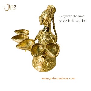 May include: A gold metal statue of a woman holding a lamp with five wicks. The statue is 5.5 inches tall and 3.5 inches wide. It weighs 0.450 kg.  Lady with the lamp 5.5x3.5 inch 0.450 kg