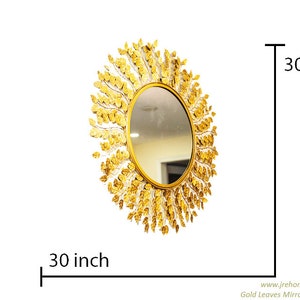 K&ouml;nnte beinhalten: Ein runder goldener Spiegel mit einem dekorativen Design aus goldenen Bl&auml;ttern um den Umfang. Der Spiegel hat einen Durchmesser von 76 cm.