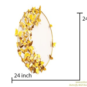 May include: Gold metal wall decor featuring a circular frame with a white background and a design of gold butterflies. The decor measures 24 inches in diameter.