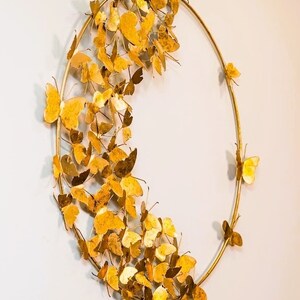 May include: Gold metal butterfly wall decor with a circular frame. The butterflies are arranged in a cascading pattern around the frame. The decor measures 24x24 inches and weighs 1.7 kg.
