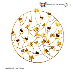 May include: Gold metal wall art featuring a circular design with a delicate, intricate pattern of branches and butterflies. The butterflies are arranged in a cluster, creating a sense of movement and whimsy. The piece is a beautiful and unique addition to any home decor.