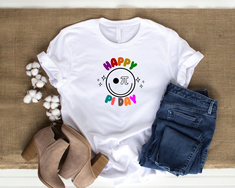 K&ouml;nnte beinhalten: Wei&szlig;es T-Shirt mit einer regenbogenfarbenen Grafik, auf der "Happy Pi Day" mit einem Smiley und einem Pi-Symbol steht.
