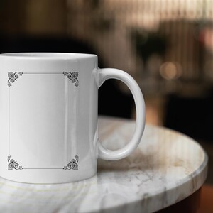 May include: White ceramic mug with a black decorative border around a blank space. The mug is sitting on a white marble surface.